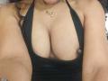 VenusChaud's big, round tits in a black halter top, showing a lot of cleavage with a small, dark areola on the right. She's wearing a gold necklace.