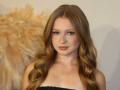 AkilahGhil has long, wavy blonde hair, light pink makeup, and is wearing a black strapless dress, showing her tits. She's looking at the camera with a slight smile.