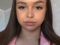 TawnyaKaczmarski has brown eyes, thick eyebrows, long brown hair, and pink lips with subtle makeup. She wears a pink patterned shirt, and has small gold earrings.