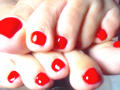 KatteRouse's red-painted toes are stacked, showing shiny, glossy, square-shaped toenails with visible white highlights. Her feet are slightly wrinkled, with soft, light skin.