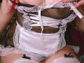MaddyMills in sheer black lingerie with white lace, ribbon, and satin, exposing her tits through the mesh, wearing white thigh-highs and a black bow on her right thigh.