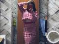 EleanoraMirabal with medium tits, wearing a red and white houndstooth crop top and matching high-waisted skirt, taking a mirror selfie in a bathroom, hand in brown hair.