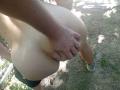 OrianaAndFriends's pale, round ass being grabbed by a tan, muscular hand. She's wearing black shorts and grey sneakers, standing on dirt with green leaves in the background.