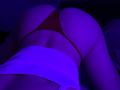 Olieri's ass in red thong, lower back exposed, white top pulled up, under purple-blue lighting, viewed from behind, kneeling position.