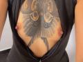 SilvanaXOwen's tits, visible through a black zip-up shirt, feature a large butterfly tattoo with intricate patterns and swirls, covering her chest. Her nipples are exposed.