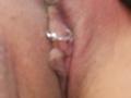 De roze vulva van FrenchShanna, met een metalen piercingring in de clitorisrand, is zichtbaar op een onscherpe foto. De focus ligt op haar geslachtsorganen..