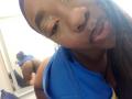JazaraKoral with dark skin, pouty pink lips, blue headband, and blue top, showing her ass in a mirror reflection, wearing a thong, with green eyeshadow.