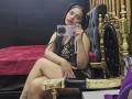 EmilyVidal with long black hair, wearing a black fishnet dress, sitting on a gold throne, taking a selfie with a glittery phone, showing her tits and ass.