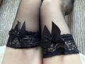 Primer plano de las piernas de Calista Swiatek, que lleva medias de red con detalles de encaje negro y adornos de lazos. Las piernas están cruzadas, mostrando patrones de tejido texturizado y material transparente. Tensión sexual implícita a través del ángulo íntimo y los detalles..