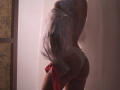 RosaVance with a sheer white lace veil, red ribbon, and white lace panties, standing in soft light, showing her ass and back, partially obscuring her face.