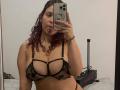 ValeryScot with curly red hair, sticking out tongue, wearing black lace bra with star patterns, showing her big tits, holding phone in mirror selfie. Steam cleaner in background.