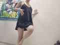 JoannaSia wearing a black, silky, spaghetti-strap dress, standing with one leg raised, her hand on the wall, showing her bare, pale, and smooth-assed thighs.
