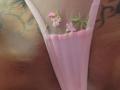 FrenchShanna's pink thong with small pink and green floral embroidery, revealing a tattooed, tan-skinned butt. The fabric is slightly sheer, highlighting her curves.