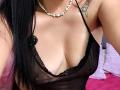 Zaria69's black sheer lingerie with lace trim, showing her tits, has a button with green lights on the left side. She's wearing a pearl necklace and has a tattoo.