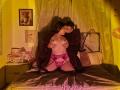 TinaYEdward with dark hair and small tits, wearing pink lace panties and garter, kneeling on bed, being kissed by TinaYEdward with short dark hair, in a dark robe.