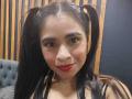 EmilyVidal with puffy brown eyes, red lipstick, black pigtails, and a shiny choker, smiling at the camera, showing her cute tits. Her ass is not visible.