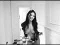 AmelieReea, topless, with long dark hair, leaning forward, wearing a black jacket and black panties, exposing her tits and holding the waistband. Black and white photo.
