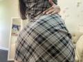 OliviaGranda's ass in a plaid skirt, her hand on her hip, wearing a matching plaid top, her long brown hair falling down. Skirt's black and white check pattern.