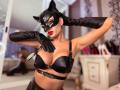 Mademoiselle Bella, con una maschera da gatto in pelle nera, guanti e reggiseno, con fibbie dorate, mostra il seno, le labbra rosse e le orecchie da gatto nere, in una posa sexy e sicura di sé..