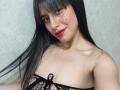 MadissonFontaine has long black hair, red lipstick, and wears black fishnet lingerie, exposing her small tits with a black ribbon. She has a nose ring and a slight smile.