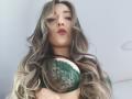 TaniaSandersX with long, wavy, blonde-green hair wearing a green lace bra, pouty lips, and a confident look, showing her big, perky tits.