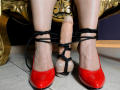 AiileenRamirez's red shiny heels with black rope, bound to a dildo with a ball, on a tiled floor, in front of a gold ornate chair.