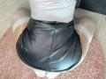 MeganHotCole is kneeling with her ass up, wearing a shiny black leather skirt, white lace-top thigh-highs, and a tight white top. Her skin is visible below the skirt.