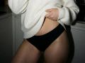 Destinis in black panties, white knitted sweater lifted to show her bare midriff, hand pulling sweater up, soft light, her curvy ass and thighs, slight shadow on skin.