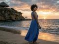 RoldanStefy with curly hair in a blue backless dress, holding a book, standing on a beach at sunset, wearing a smile, looking over shoulder, ocean in background.
