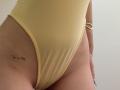 SugarrX's yellow thong-ass, showing a small tattoo on the left thigh, with a gold bracelet on the right wrist and a subtle tan line.