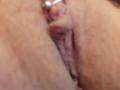 FrenchShanna's pussy, shown in a blurred, close-up shot, with visible labia and a small, metal piercing on her clitoral hood. Her skin is light brown with subtle texture.