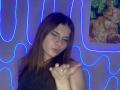 HeikeRippy with brown hair, wearing a black top, winking, and pouting with fingers up, neon blue lights in background, and a photo of a cat with money in the corner.