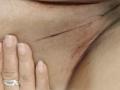 VonneLucia's hand with a silver ring is gently touching her close-shaved, slightly red, and textured pussy. Her fingers are near her inner labia.