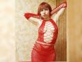 LaylaHottyX with red fishnet dress, arms raised, exposing her tits through diamond pattern, red hair, fair skin, standing in room, looking at camera with serious expression.