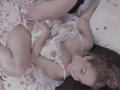 AmberDemons lies on a bed, wearing a polka dot lingerie set, with her hand on her pussy, legs spread, curly brown hair, and a seductive gaze.
