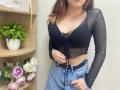 Rioria has a black sheer top with a deep V, showing her boobs, and a blue denim skirt. She's tugging at her belt, with brown hair, in a photo.