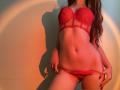FlyFreedom wearing red lace lingerie, showing her tits and pussy, with her hand pulling down the lace panties, shadow on the wall, long wavy brown hair.