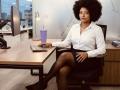 RoldanStefy, black woman with big afro, white shirt, black skirt, and black stockings, sitting in office chair, typing on keyboard, with purple drink on desk.