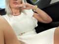 Hotsexydolly in a white dress, sitting in a car, with her legs spread, showing her thighs, wearing a gold watch and diamond bracelet, touching her pink lips.