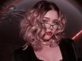 AdrianePittillo with pink curly hair, green glasses, black choker, black top, looking seductively at the camera, showing a little cleavage, with a slightly open mouth.
