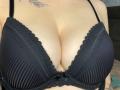 Olieri's black lace braed boobs with ribbed texture, small black bow, and visible cleavage, showing a leaf tattoo on her upper chest.