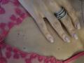 TenerliRize's hand with pink-nail polish rests on her tan-skinned chest, wearing a pink lace top with heart patterns, showing a silver ring with three bands.