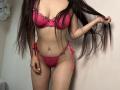 Tisia with long dark hair, wearing a pink lace bra and matching panties, holding her hair. She has small tits and a slim, sexy ass. Her panties are tied.