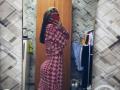 EleanoraMirabal in a red and white houndstooth dress, showing off her big ass and small tits in a mirror selfie, holding a red phone, with long brown hair.