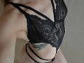 Le soutien-gorge en dentelle noire de GwynBartell, qui dévoile ses seins, associé à des culottes noires à fines bretelles, révélant un tatouage sur le bas de son ventre, et un côté de sa peau pâle..