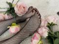 MiraRosse's feet in black fishnet stockings, with pink roses scattered around, lying on a white fluffy surface. Her toenails are painted dark. Soft, sensual, and pretty.