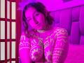 MaddieLesYoux with glowing neon pink and green tattoos, large breasts, leaning forward with a seductive expression. Purple neon light background, red folding screen on the left. Sexual tension.
