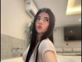 RoxanneeSecret with long black hair, red lipstick, and a white wet t-shirt, pouting her plump lips, showing her small, perky tits, in a bathroom.
