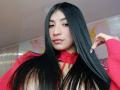 NaiaSanders has long black hair, wearing a red hoodie, with a nose ring and pink lips, looking at the camera with a slight smile, showing off her nails.