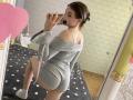 KaiaLein, butt in a grey ribbed off-shoulder sweater, kneeling, taking a mirror selfie, showing her ass, white socks, brown hair in a bun, holding a pink phone.